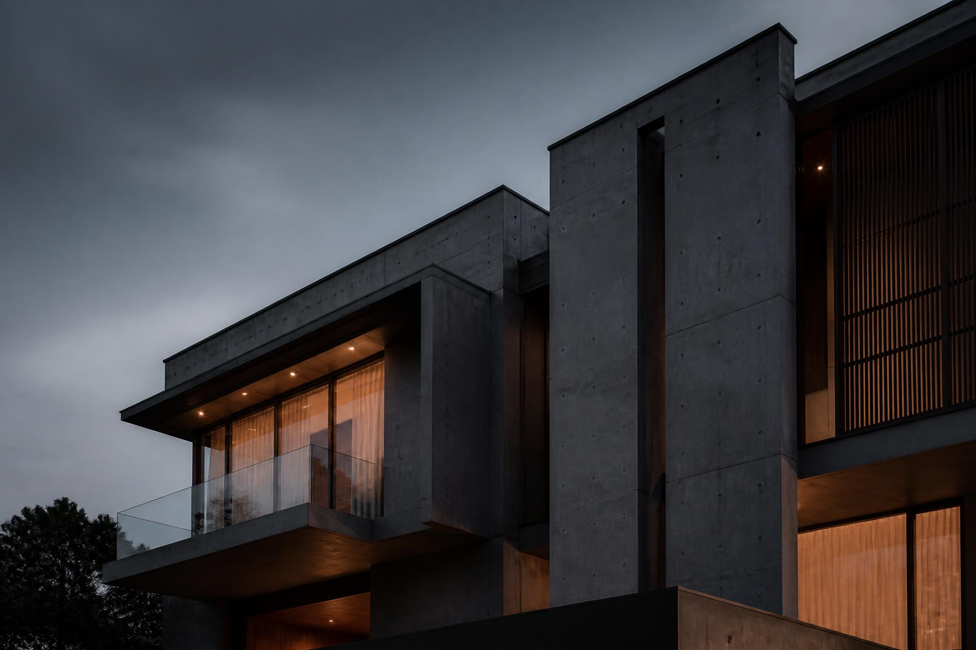 Fachada de edificação contemporânea em concreto e vidro ao anoitecer